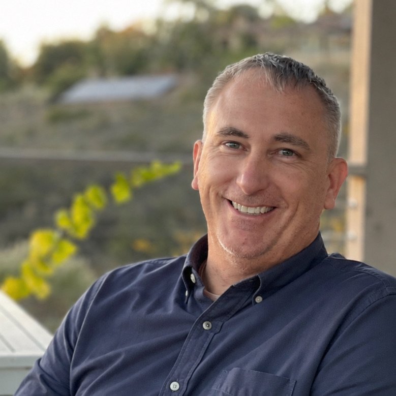 Teague Bode, founder of The Pathfinder Project, smiling in an open-collar shirt on a porch